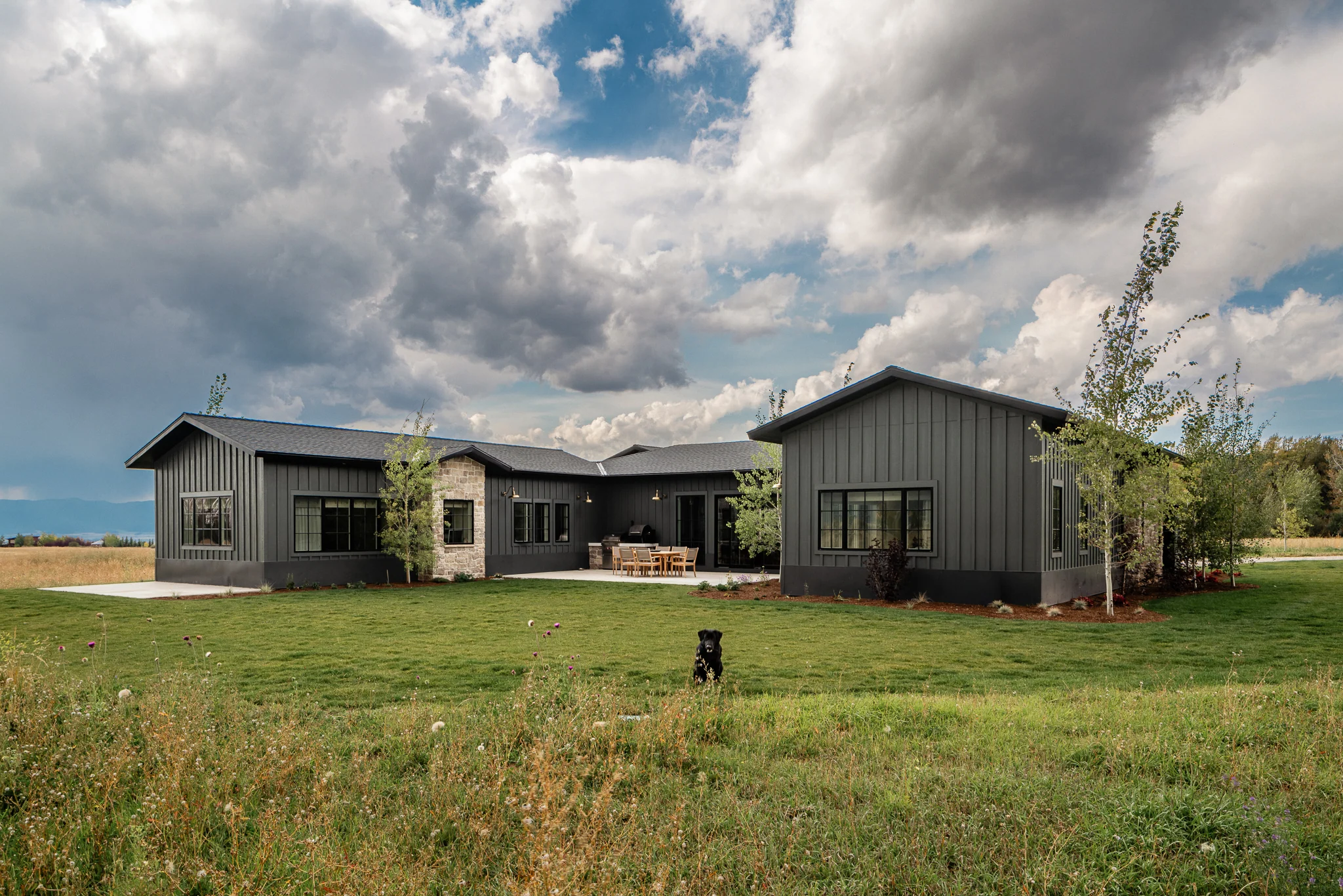 Exterior view of the home with a dog crossing the lawn — architectural photography Driggs Idaho, WTG Architects